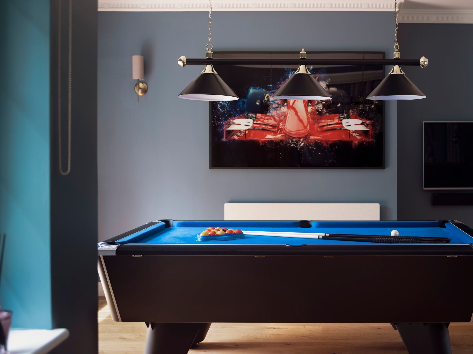 Knebworth games room with blue‑baize pool table, triple pool light and racing artwork on deep blue walls.