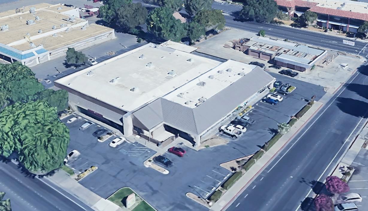 An aerial view of a large building with a parking lot in front of it.