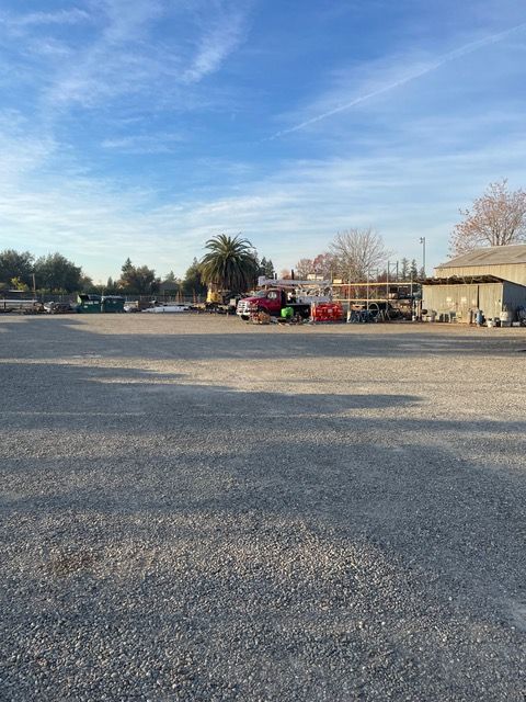 a lot of trucks are parked in a gravel lot .