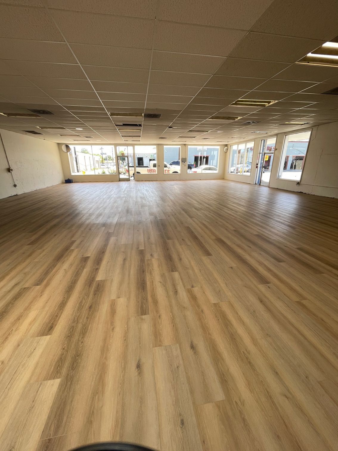 A large room with a wooden floor and lots of windows.