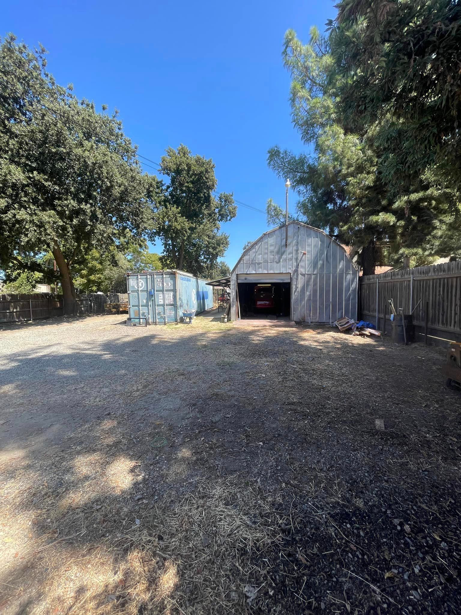 There is a garage in the backyard with trees in the background.