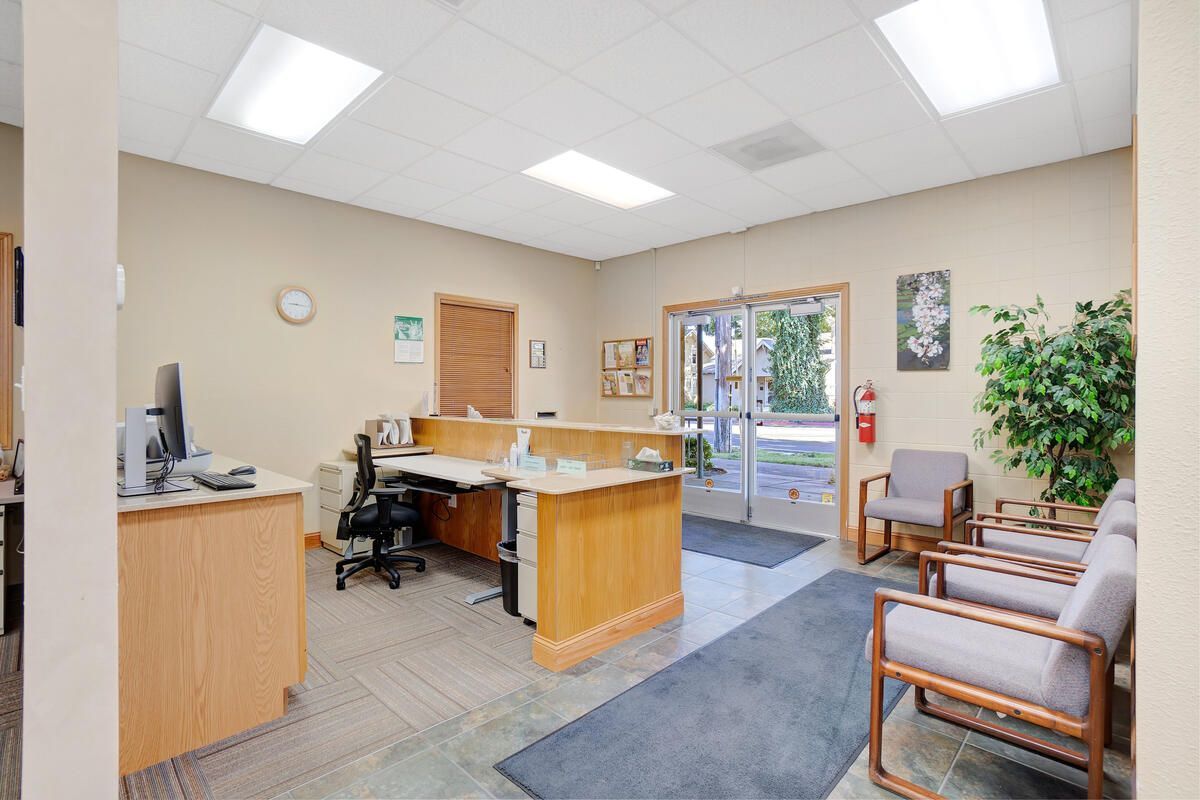 Office reception area with a desk, chairs, and door leading outside.
