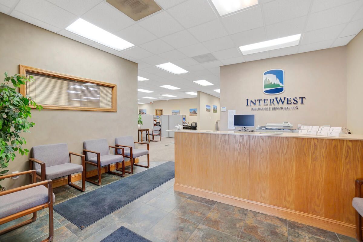 Reception area of InterWest Insurance, with chairs, desk, logo and view to office area.