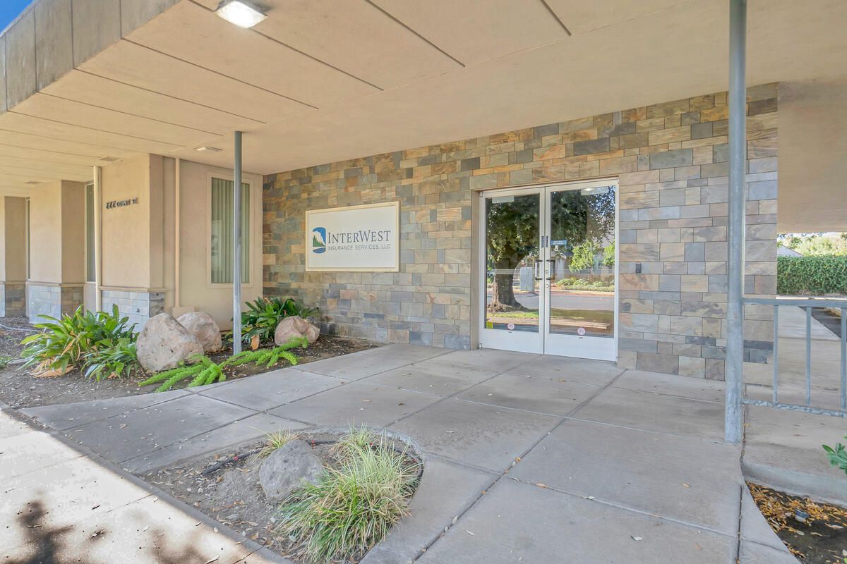 Entrance to a building with stone facade, glass doors, and a sign that reads 