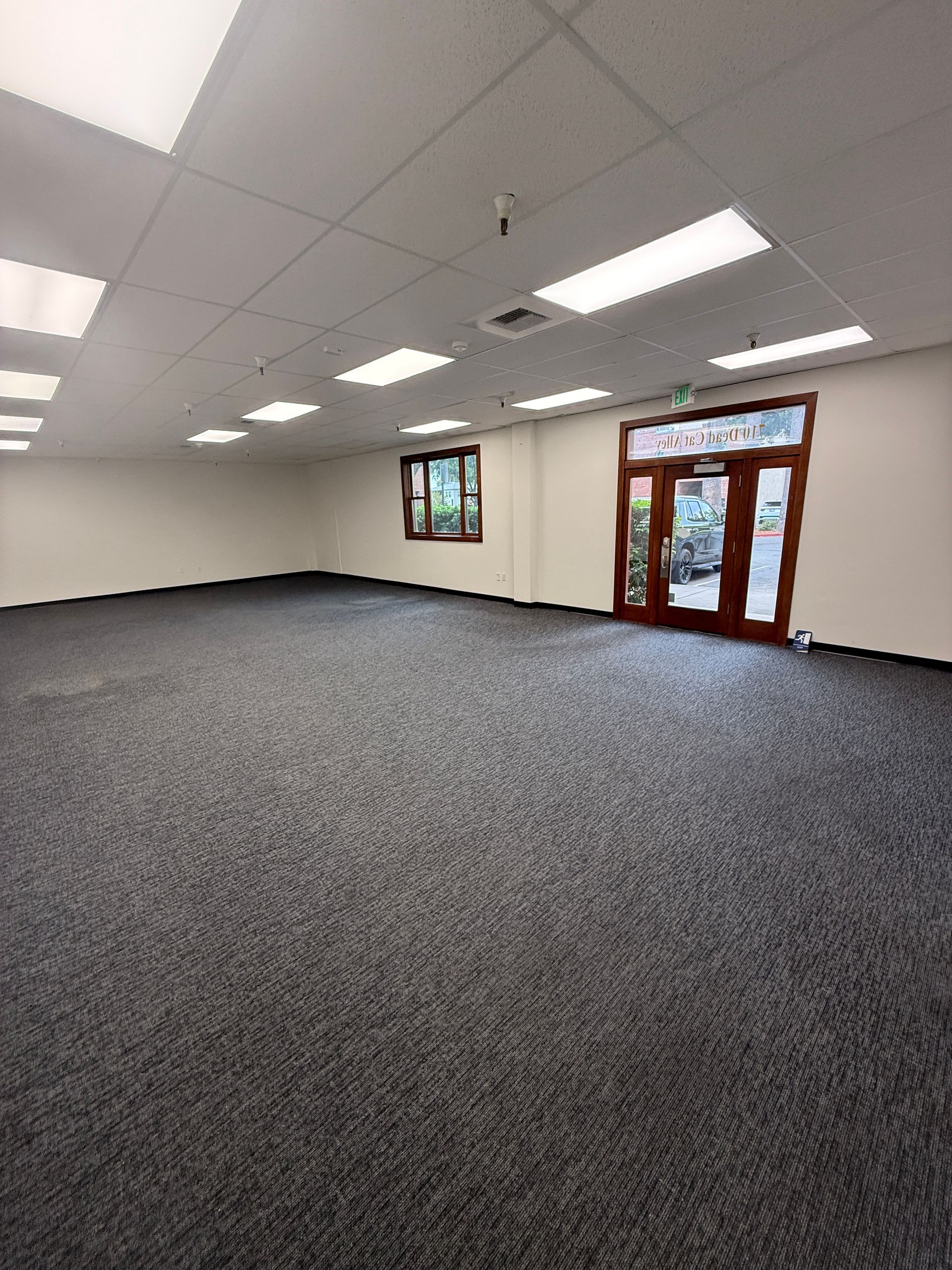 Empty room with gray carpet, white walls, recessed lighting, and a double door.
