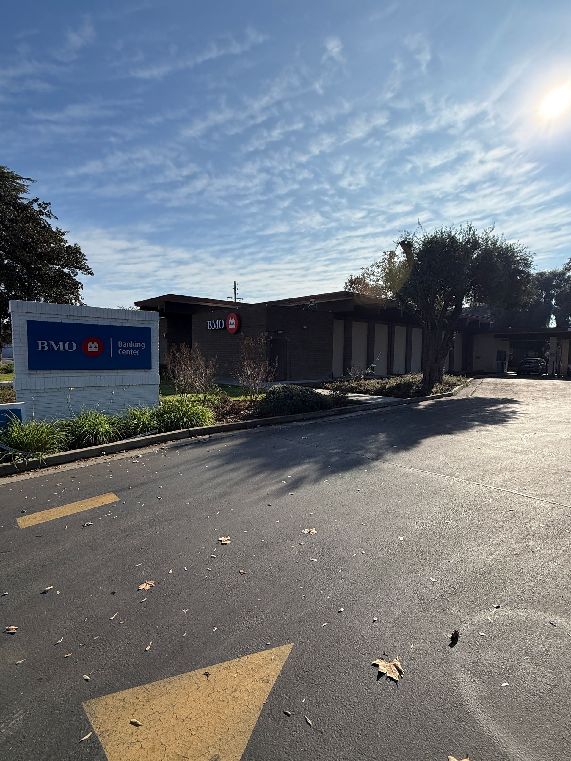 A low, brick building with a sign and driveway under a blue sky.