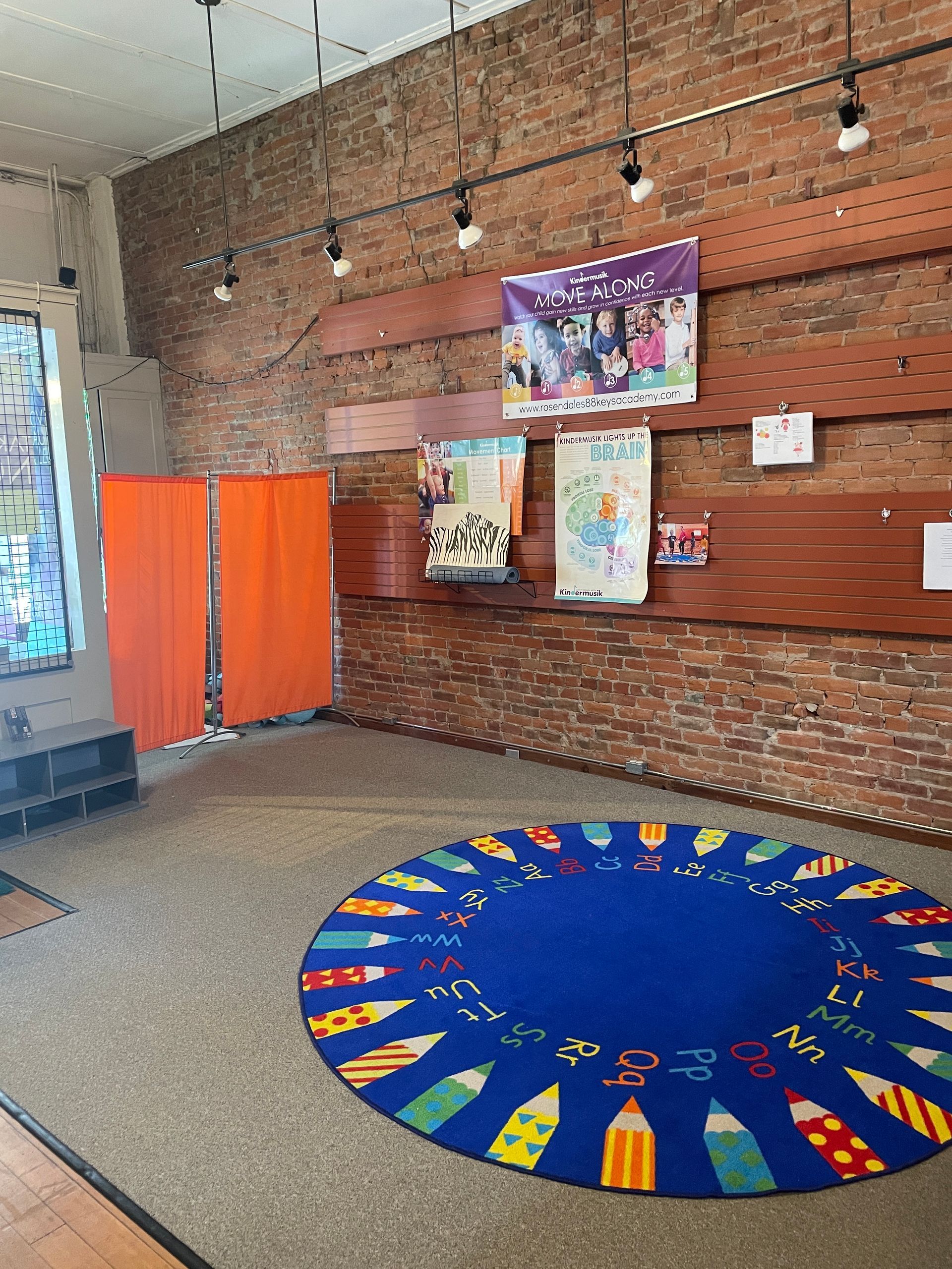 A blue rug with pencils on it is in a room with a brick wall.