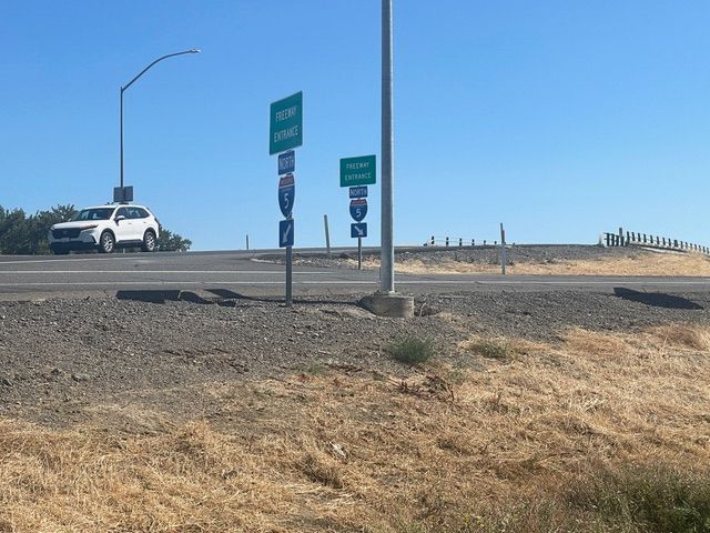 A white suv is driving down a road next to two green signs