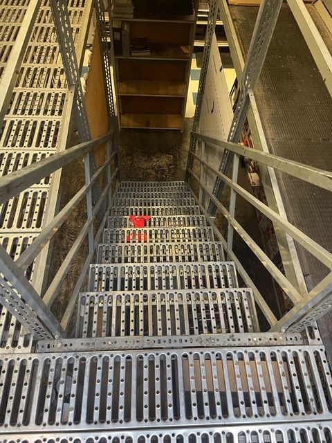 A metal staircase with a red ball on the bottom step