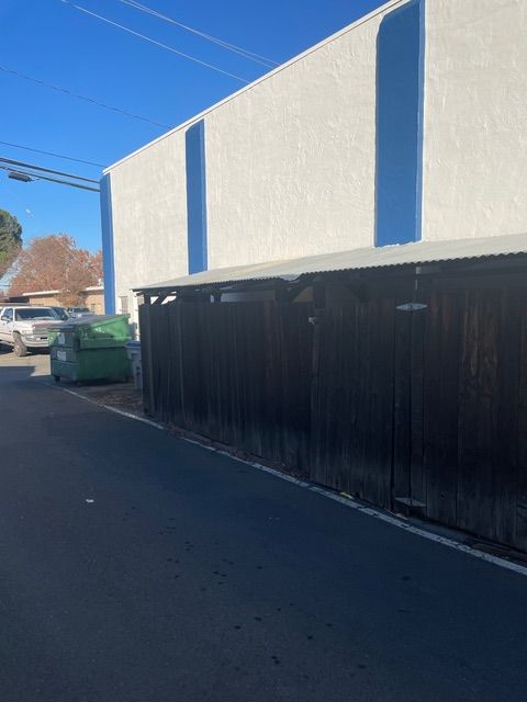 A white building with a green dumpster in front of it