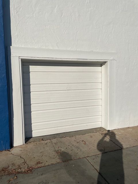 A white garage door is on the side of a white building.