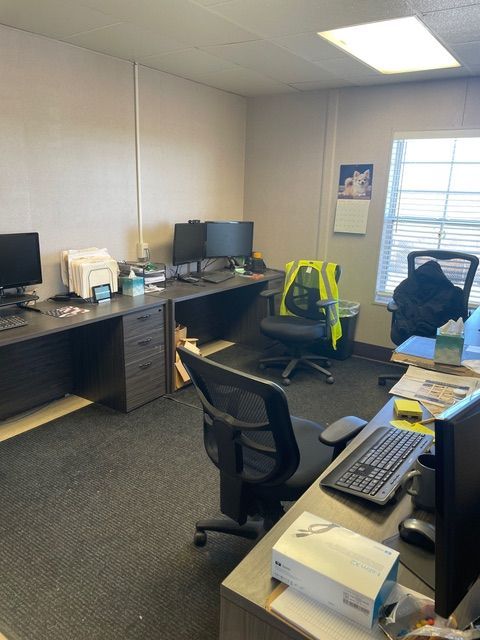 Office interior with desks, computers, chairs, and a window.