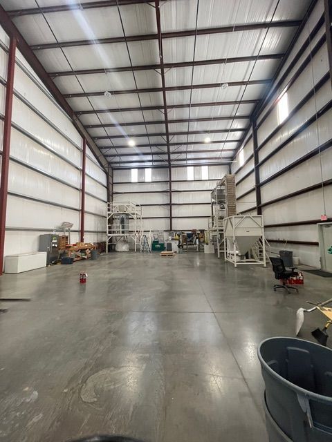 Large warehouse interior with industrial equipment and a concrete floor.