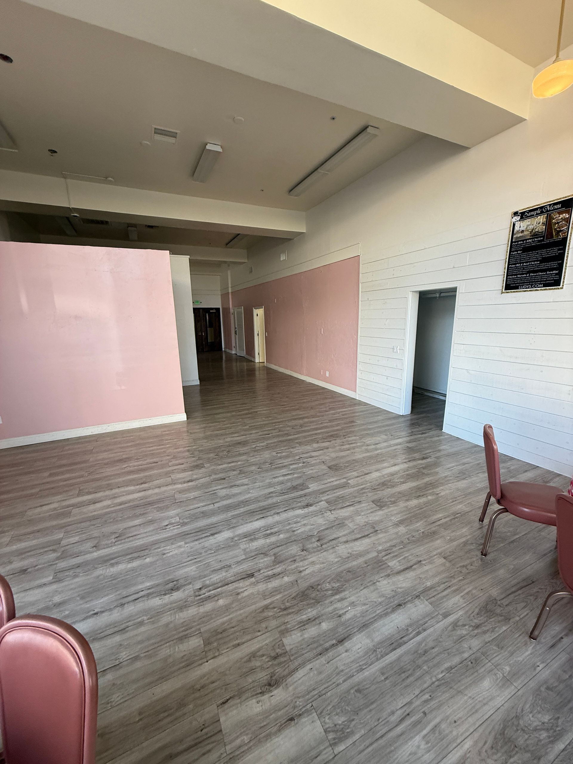 A large empty room with wooden floors and pink chairs.