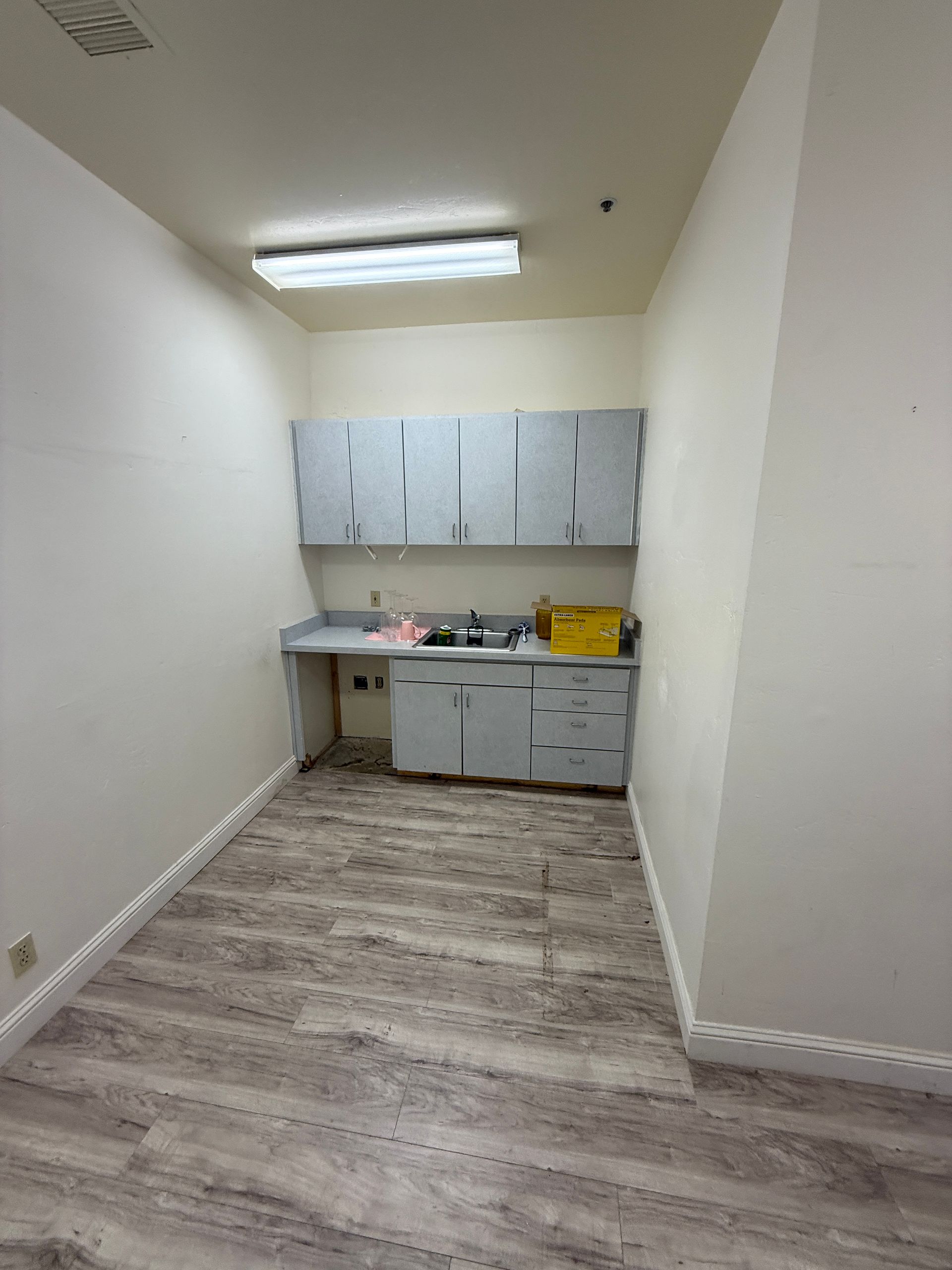 A kitchen with a sink , cabinets , and wooden floors.