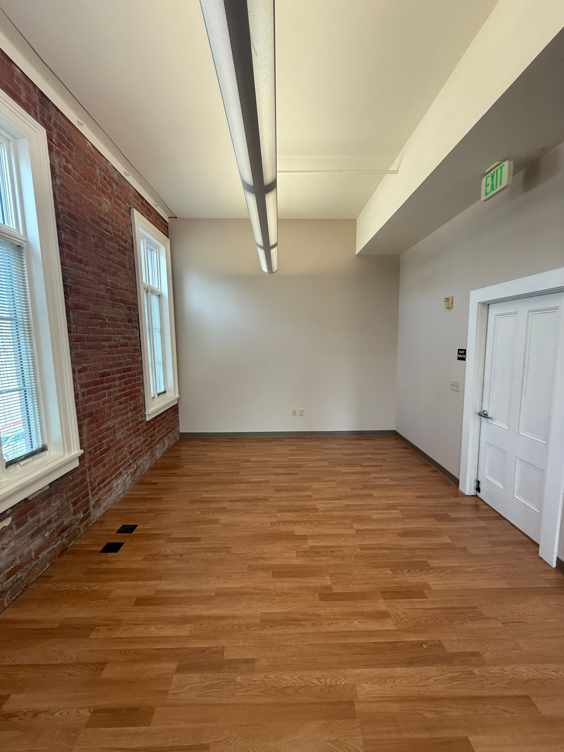 A large empty room with hardwood floors and brick walls.