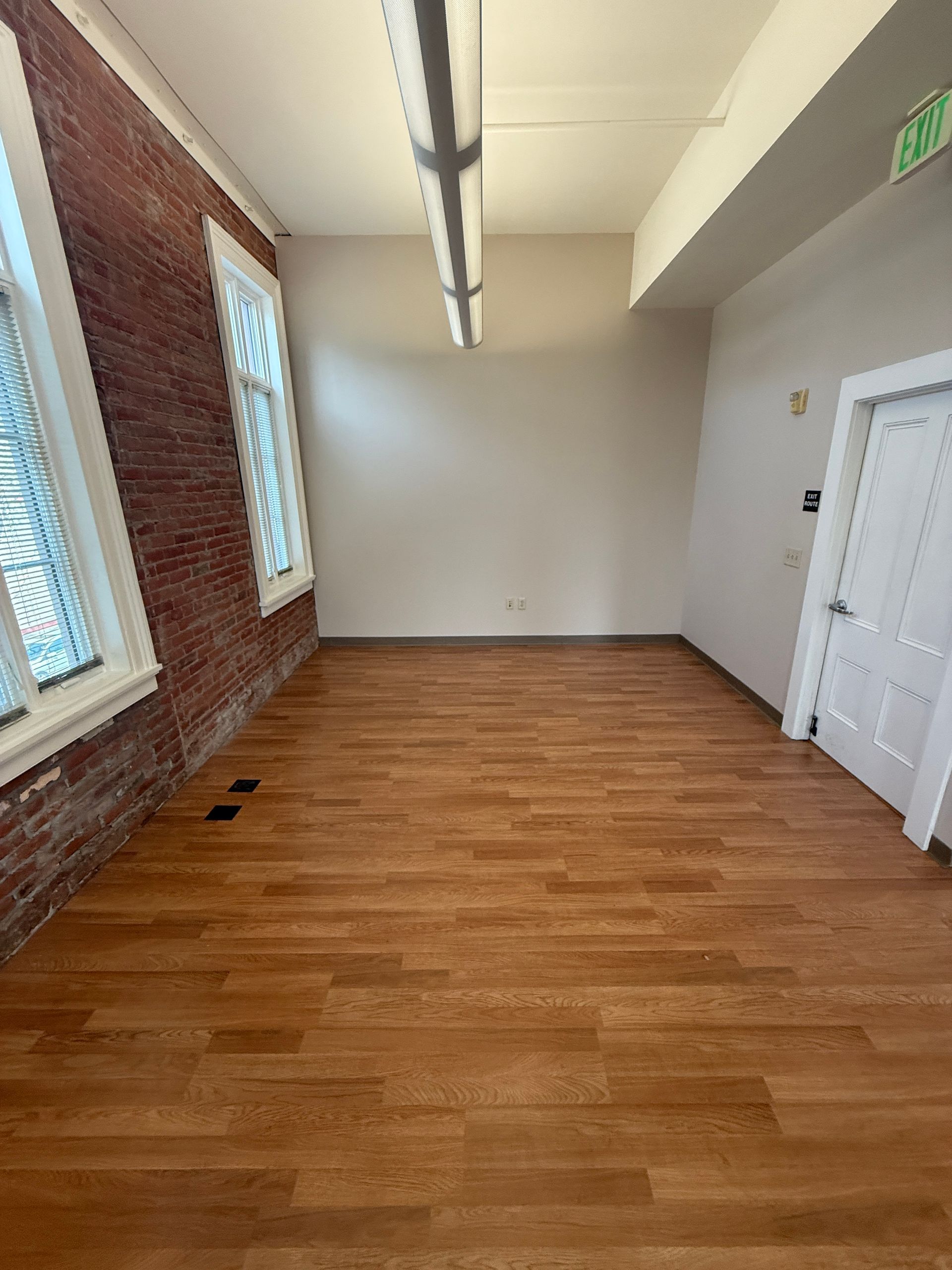 An empty room with wooden floors and brick walls.