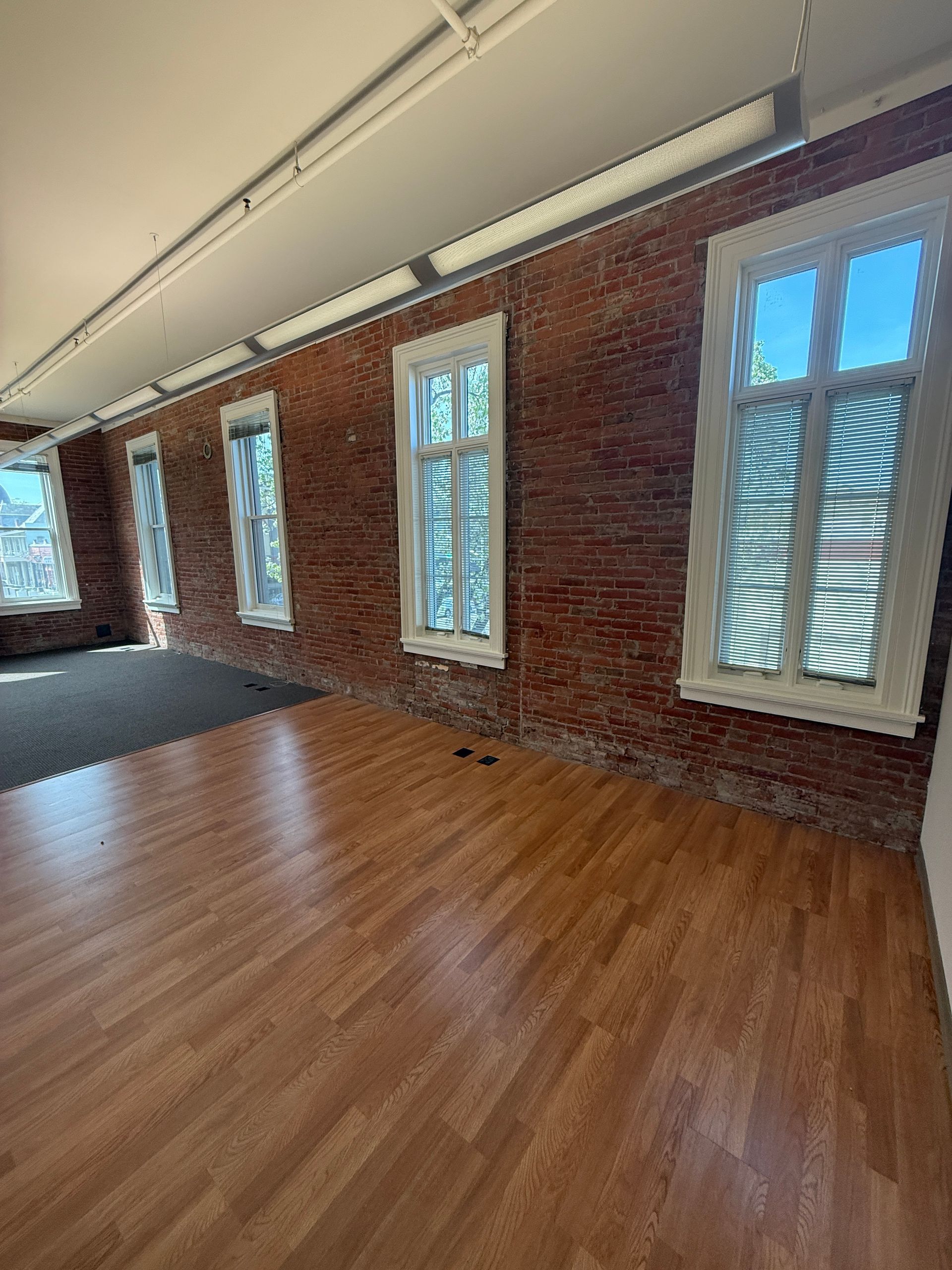 A large empty room with hardwood floors and brick walls.