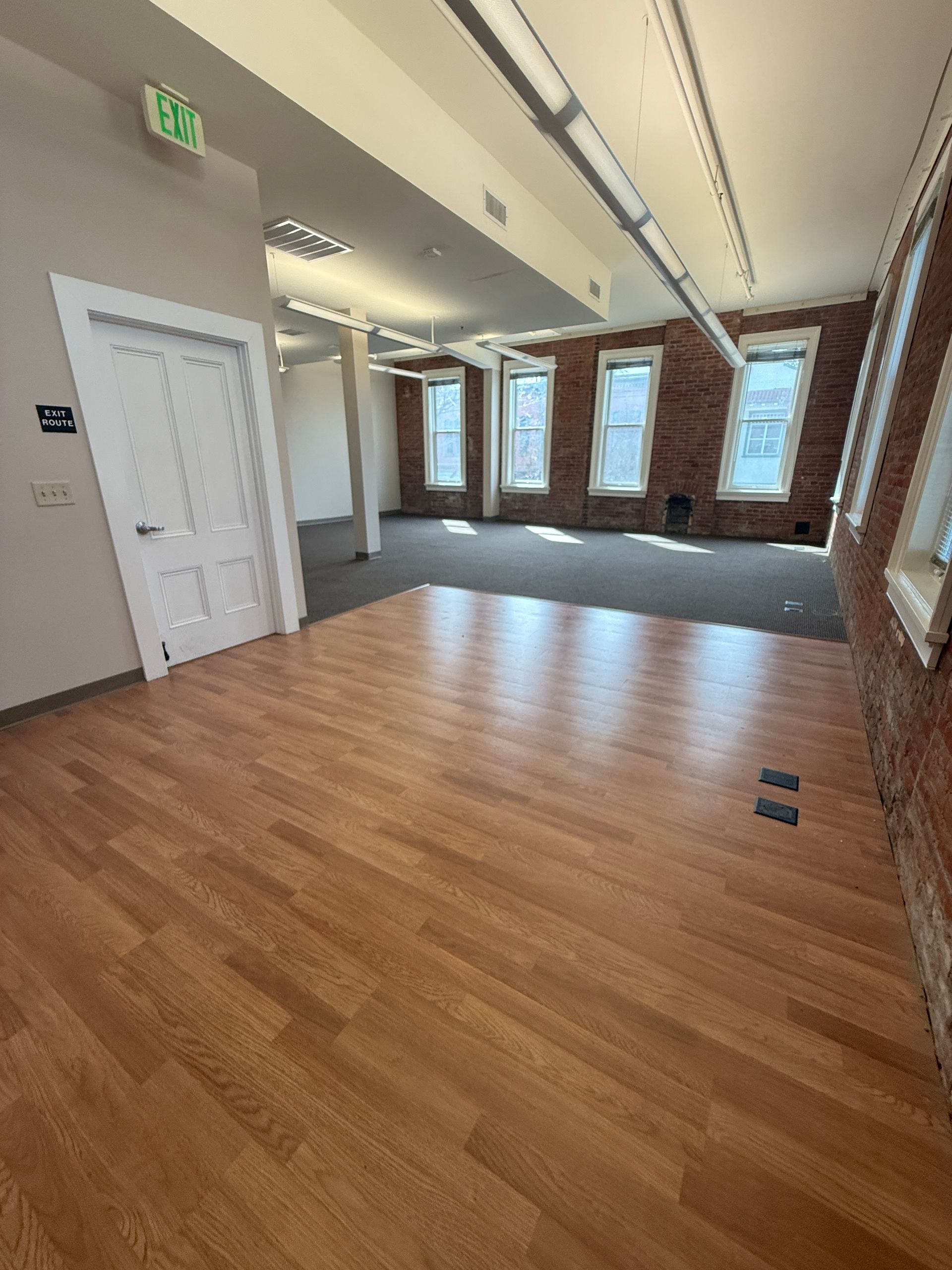 A large empty room with wooden floors and brick walls.