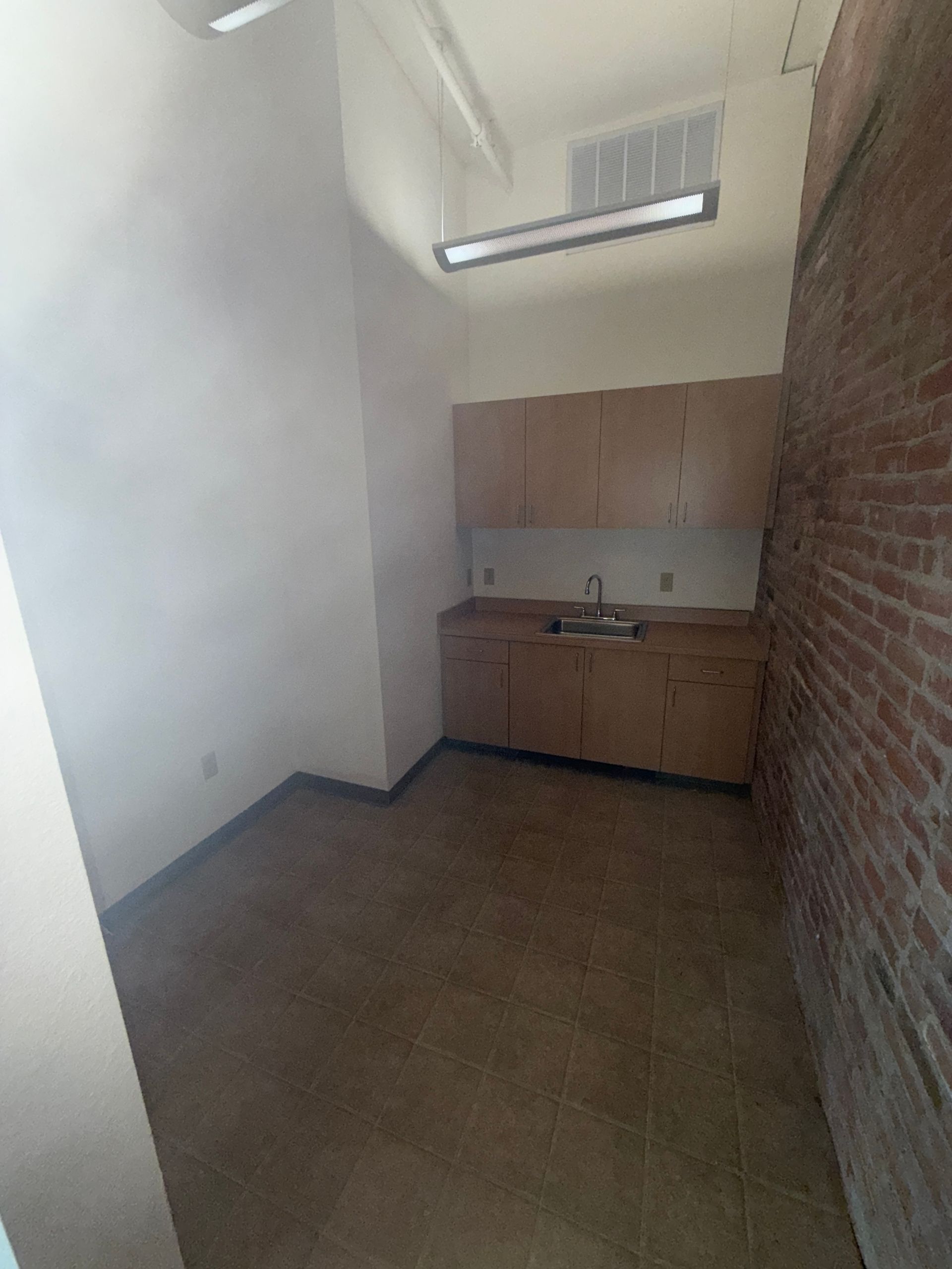 A kitchen with wooden cabinets and a brick wall