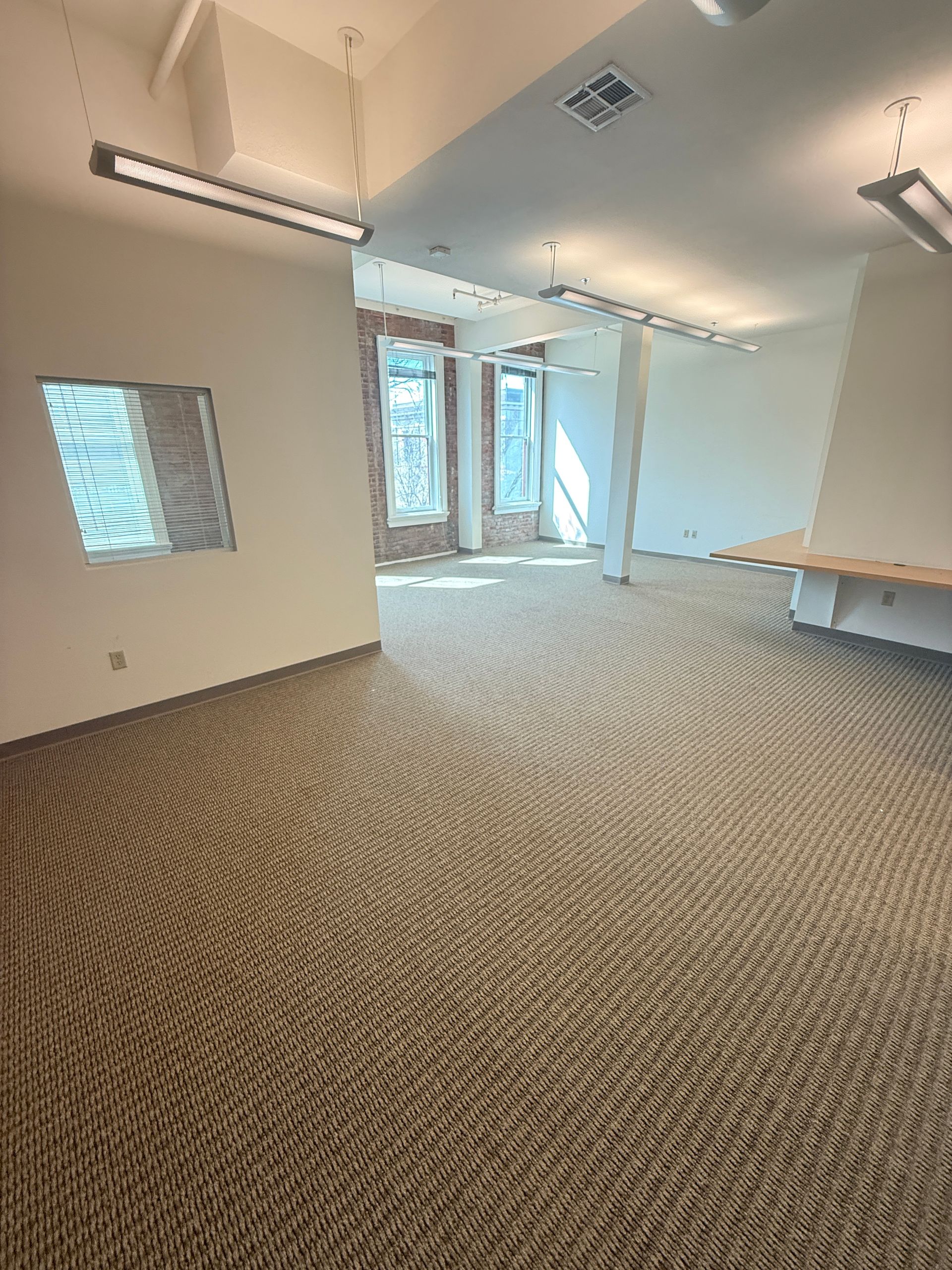 An empty room with a carpeted floor and white walls.