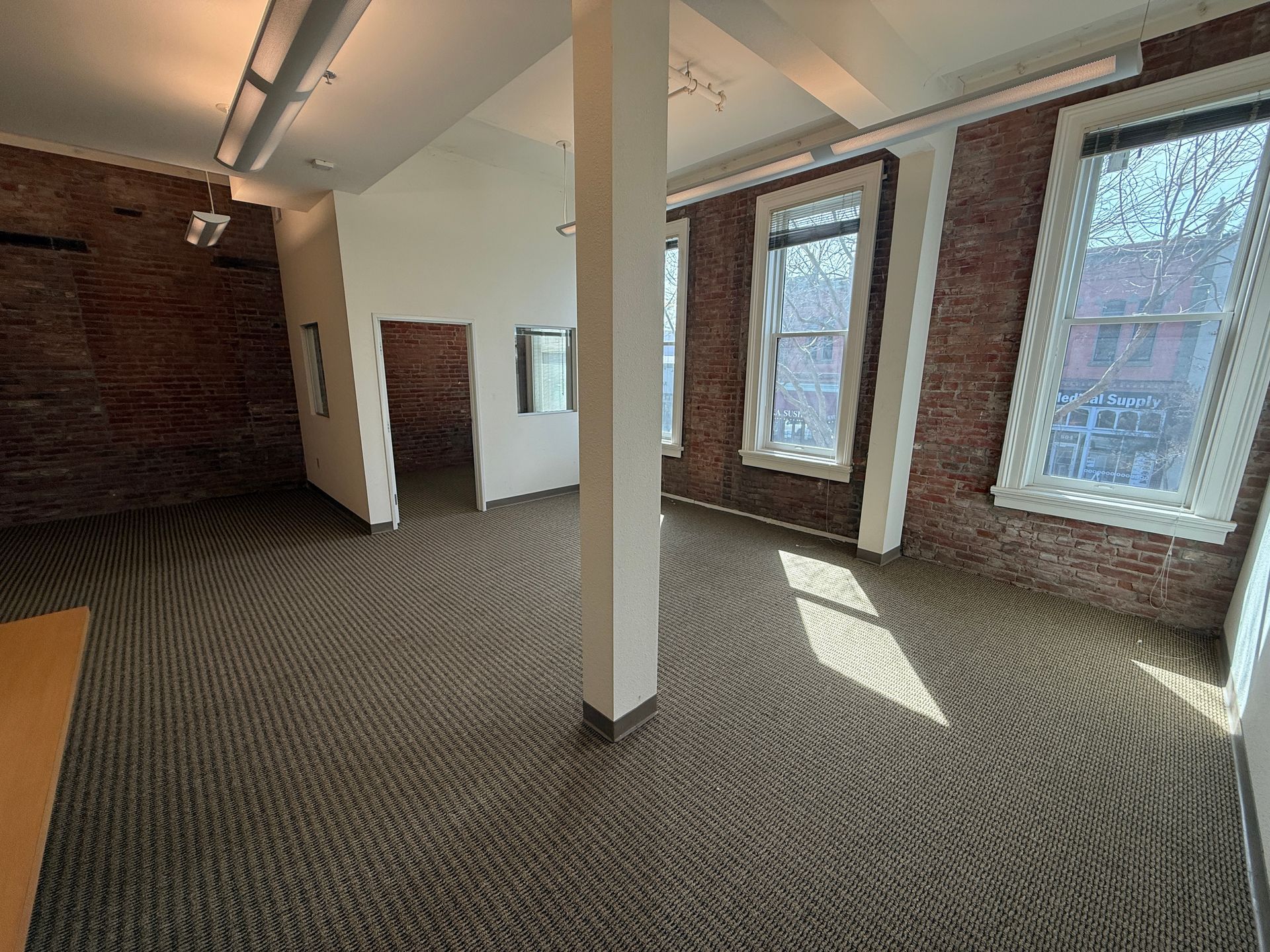 An empty room with a brick wall and a lot of windows.