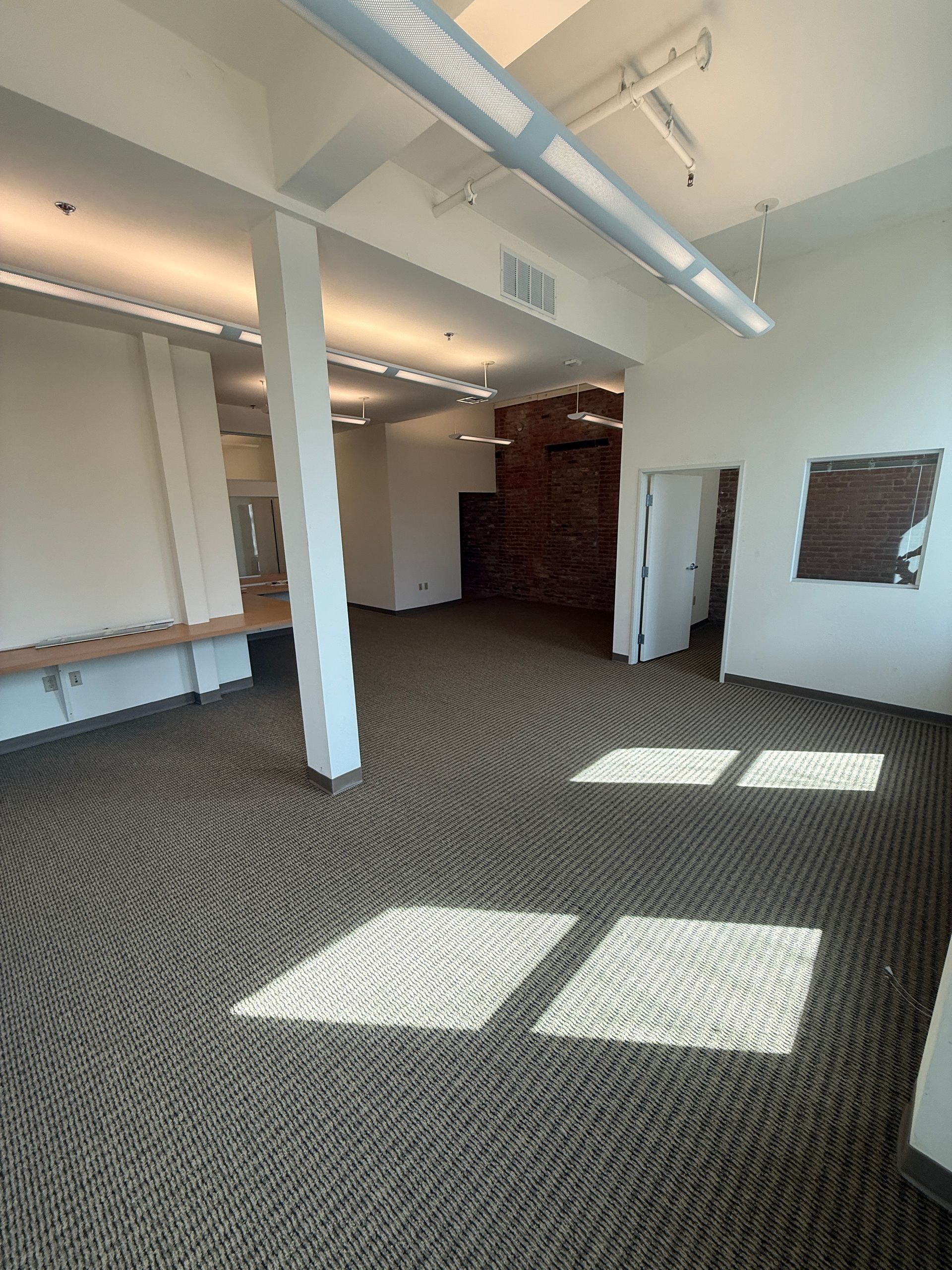 A large empty room with a brown carpet and white walls.