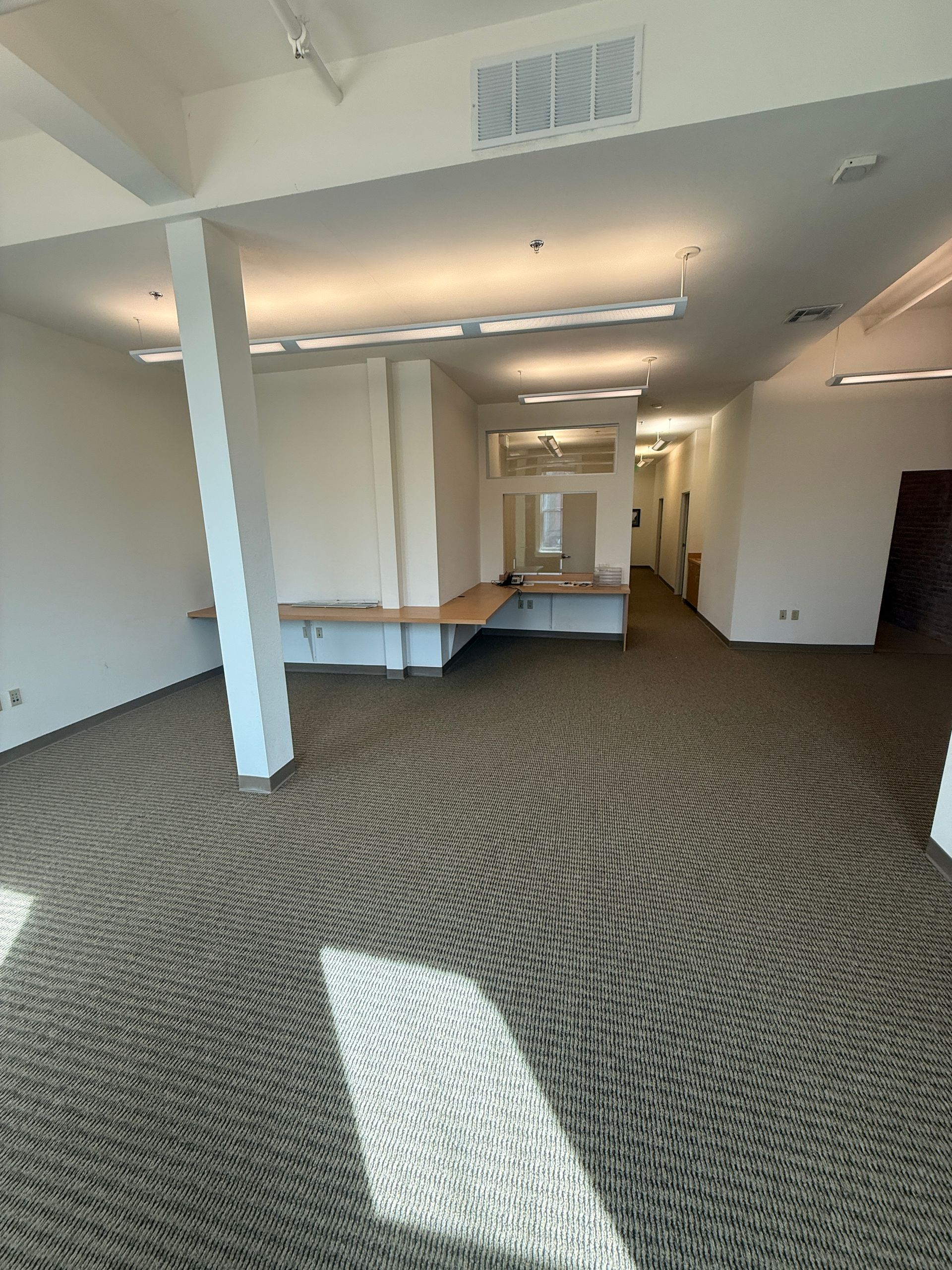 A large empty room with a carpeted floor and white walls.