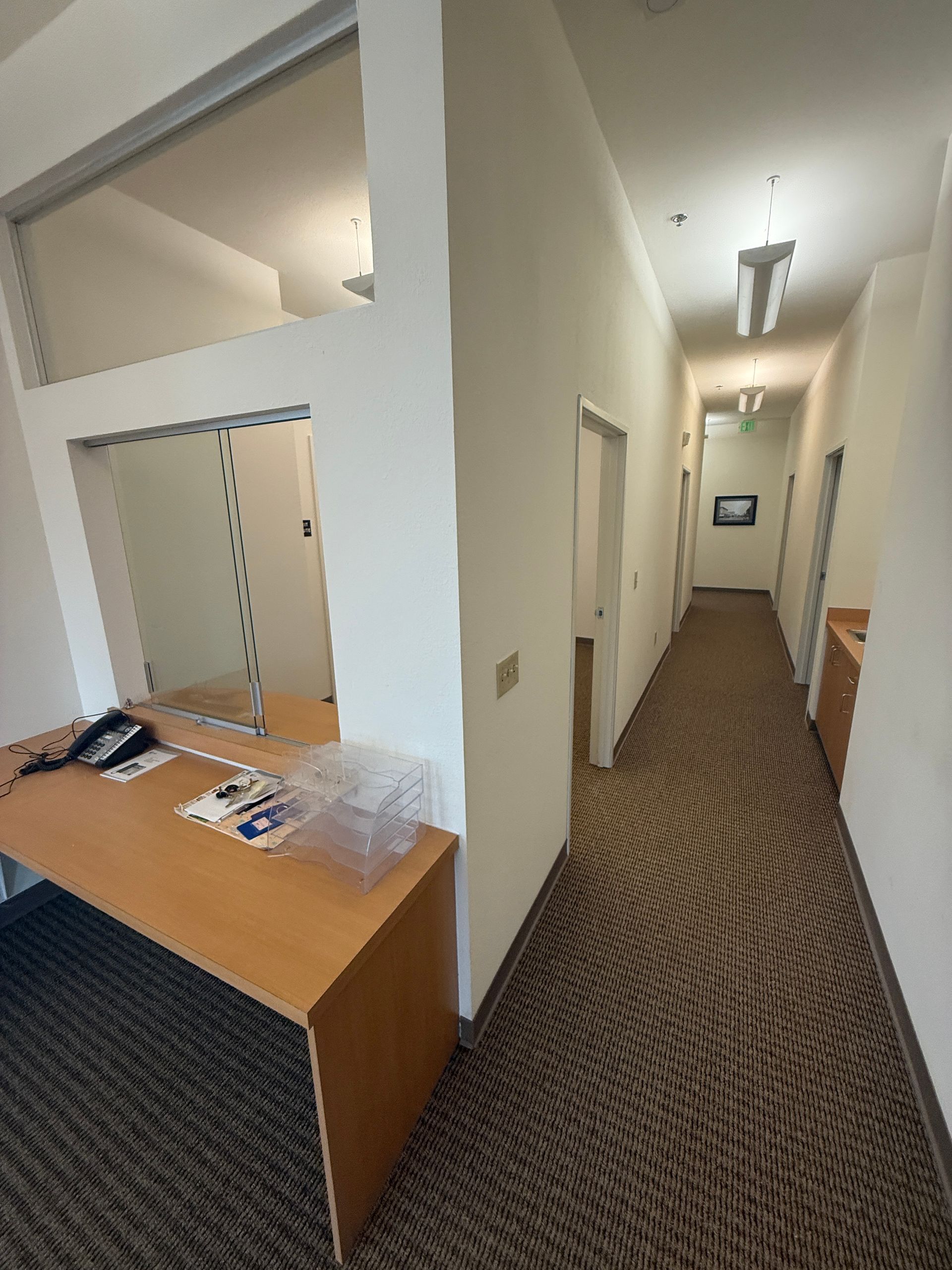 A long hallway with a desk in the middle of it