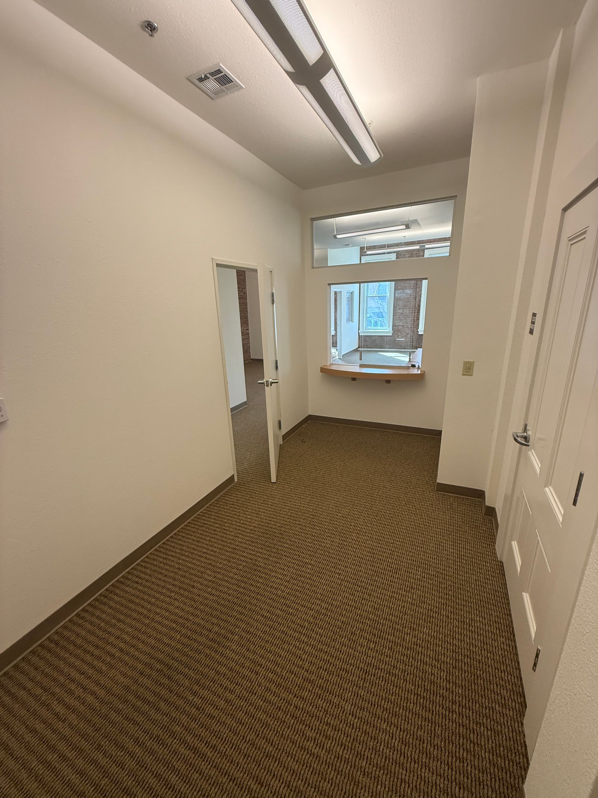 An empty hallway with a carpeted floor and a window.