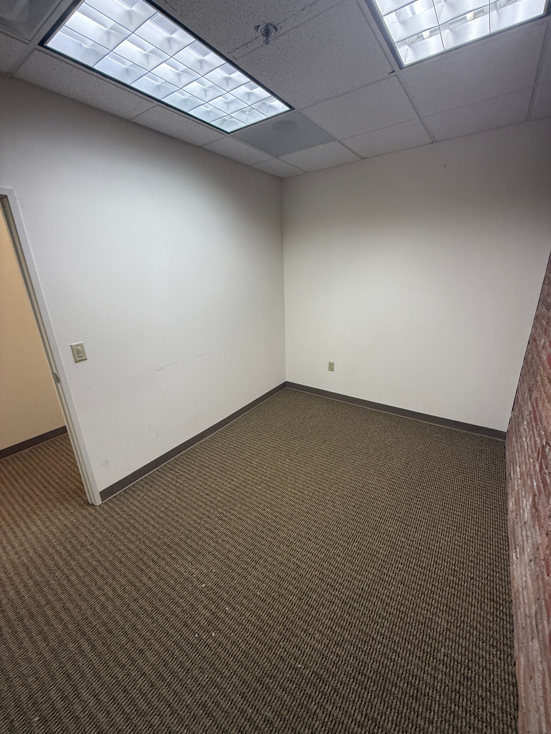 An empty room with a carpeted floor and white walls.