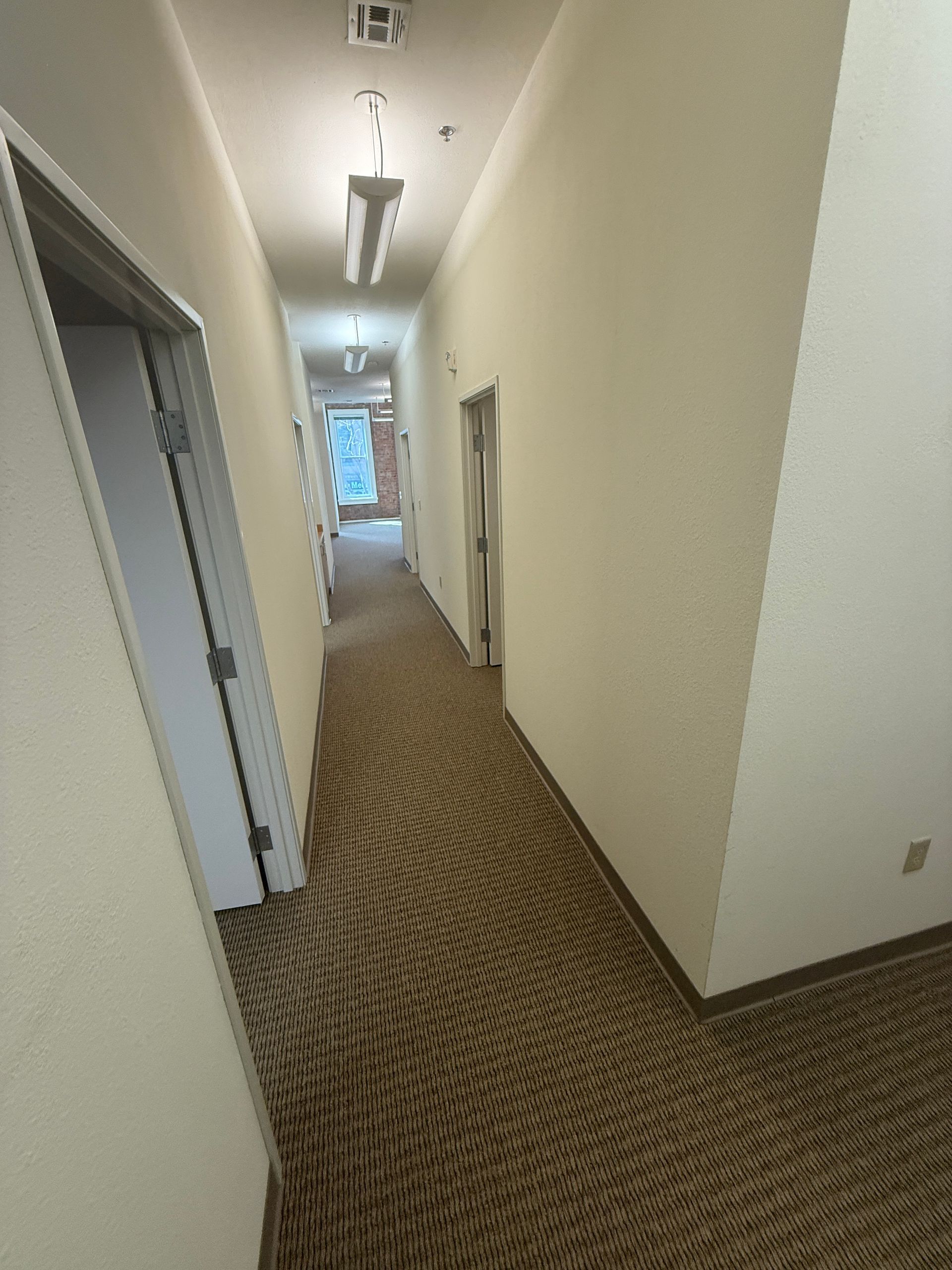 A long hallway with a carpeted floor and white walls.
