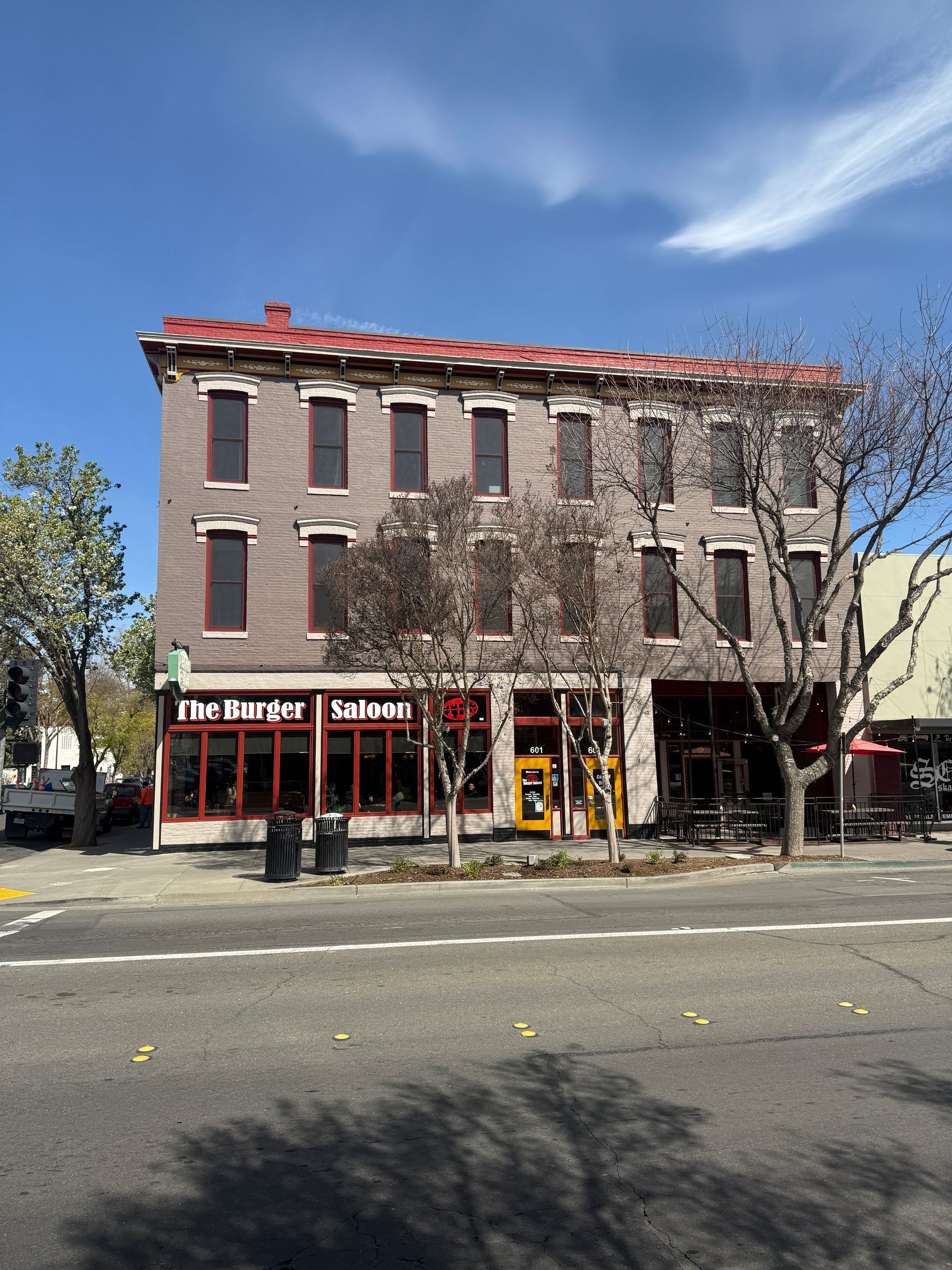 A large brick building with a red roof is on the corner of a street.