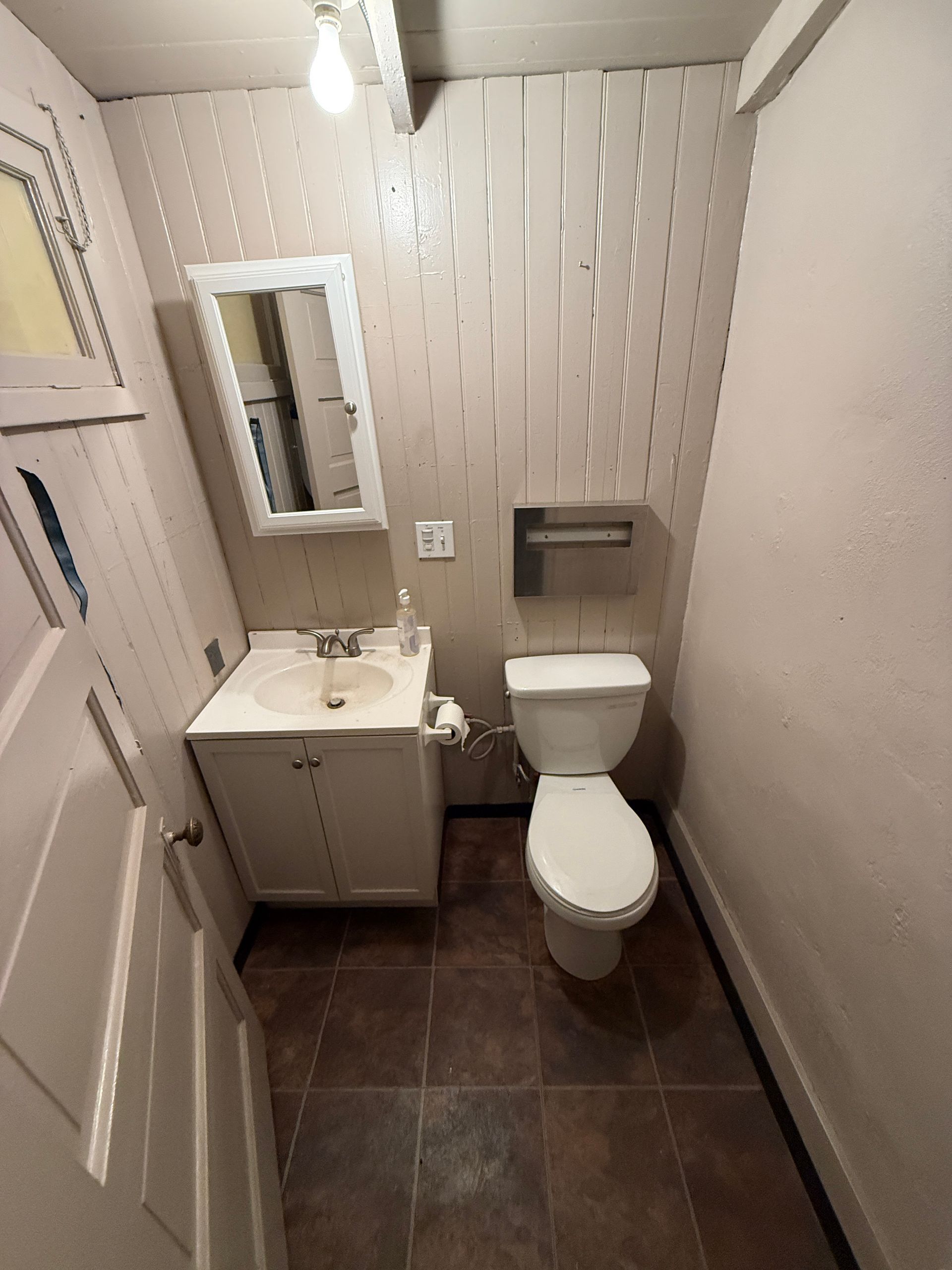 A bathroom with a toilet , sink and mirror