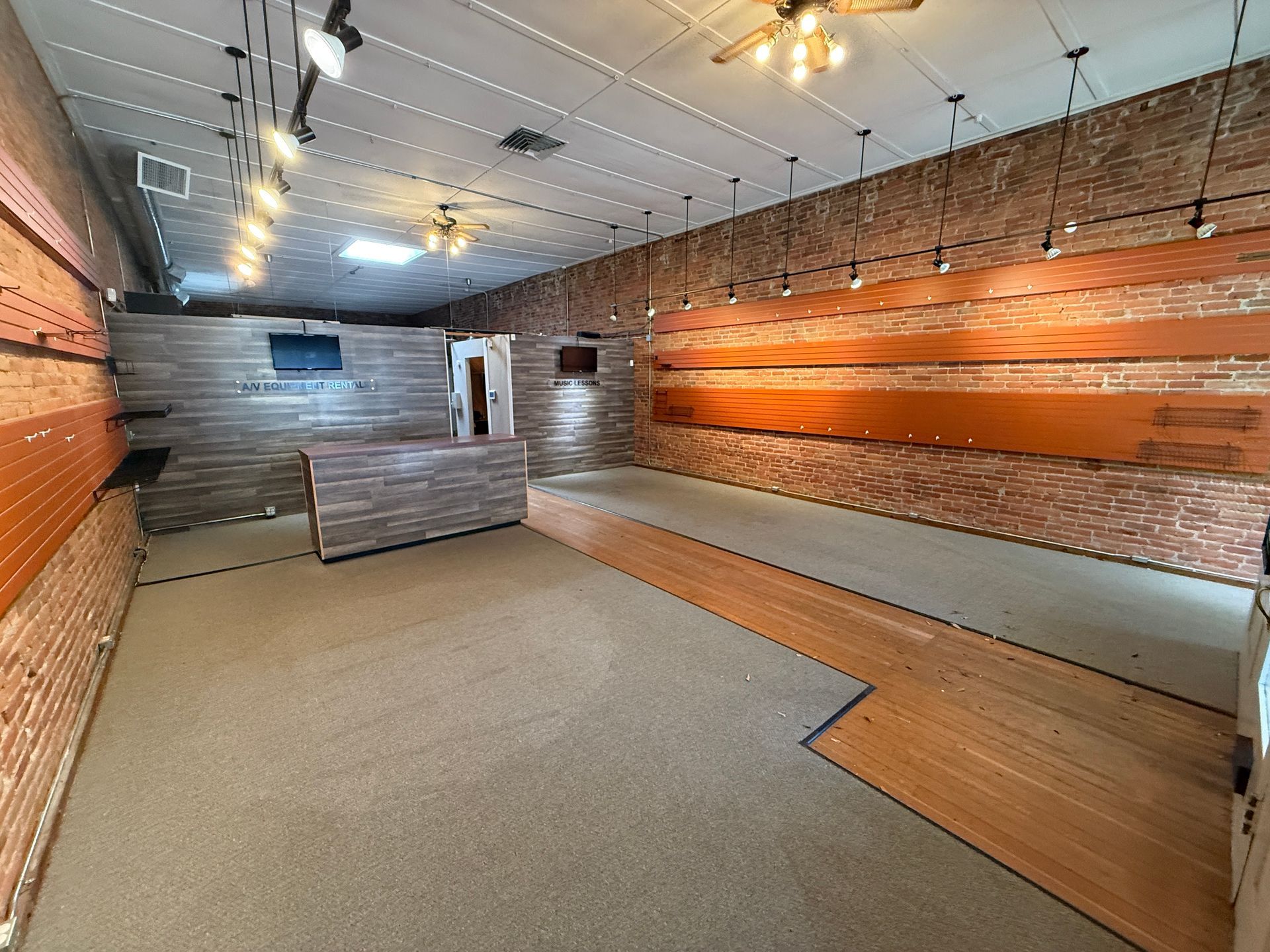 A large empty room with a wooden floor and brick walls.
