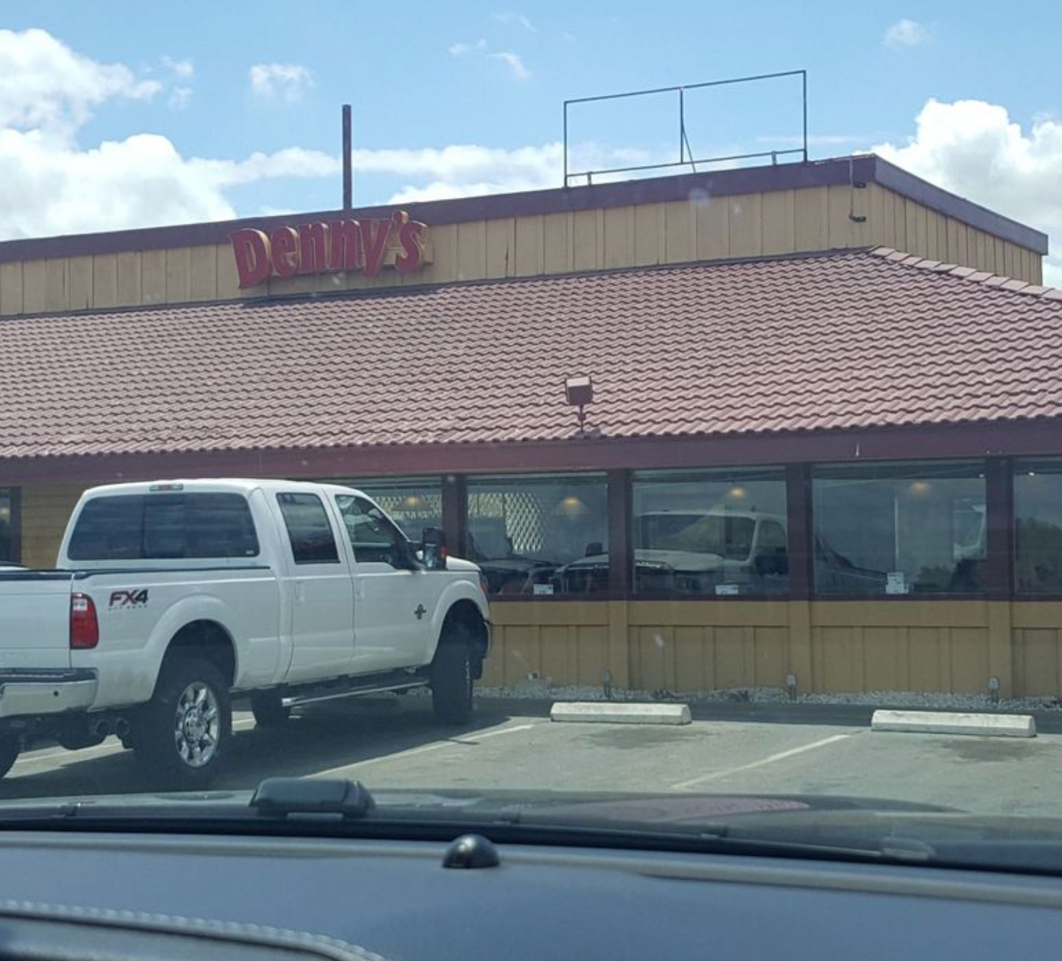 White pickup truck parked outside of a restaurant, D'Amico's, with red roof and sign.