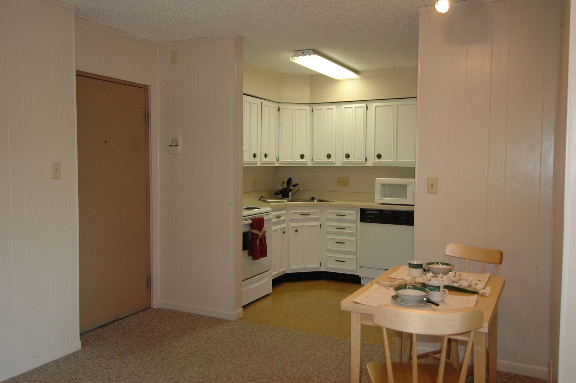 Photo showing a small dining area in the foreground and a kitchen in the background