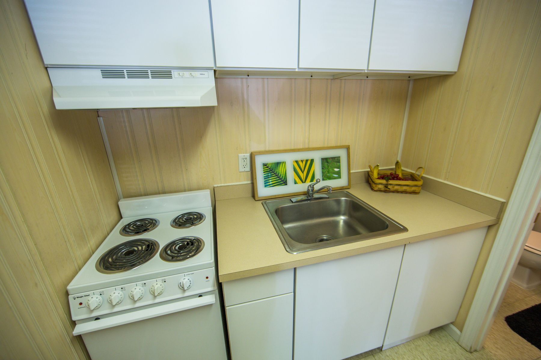 Photo showing a small kitchen with a 4 burner stove and a sink