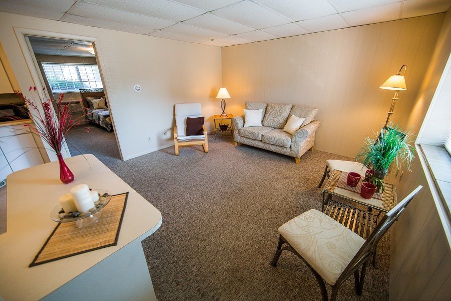 Photo showing a living room in the foreground with a bedroom in the background