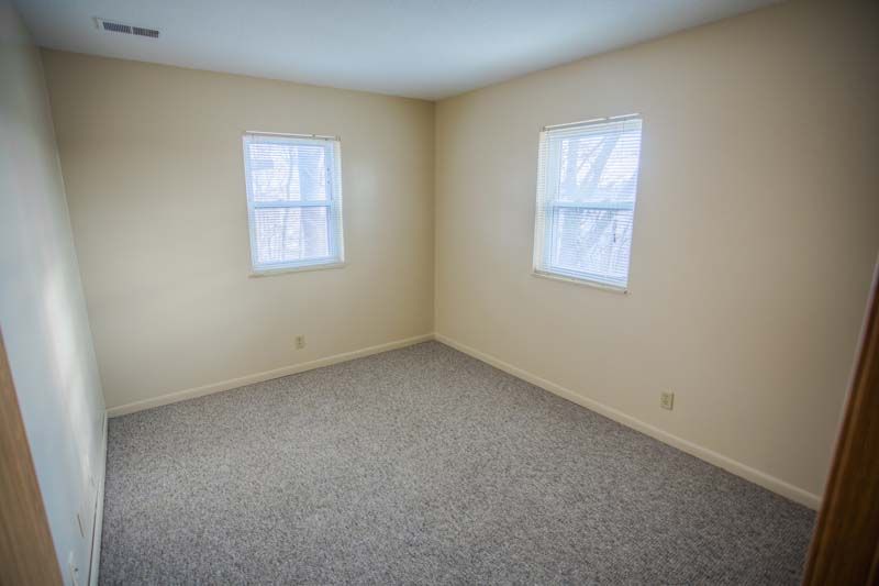 Photo showing a bedroom with two windows, seen from an alternate angle