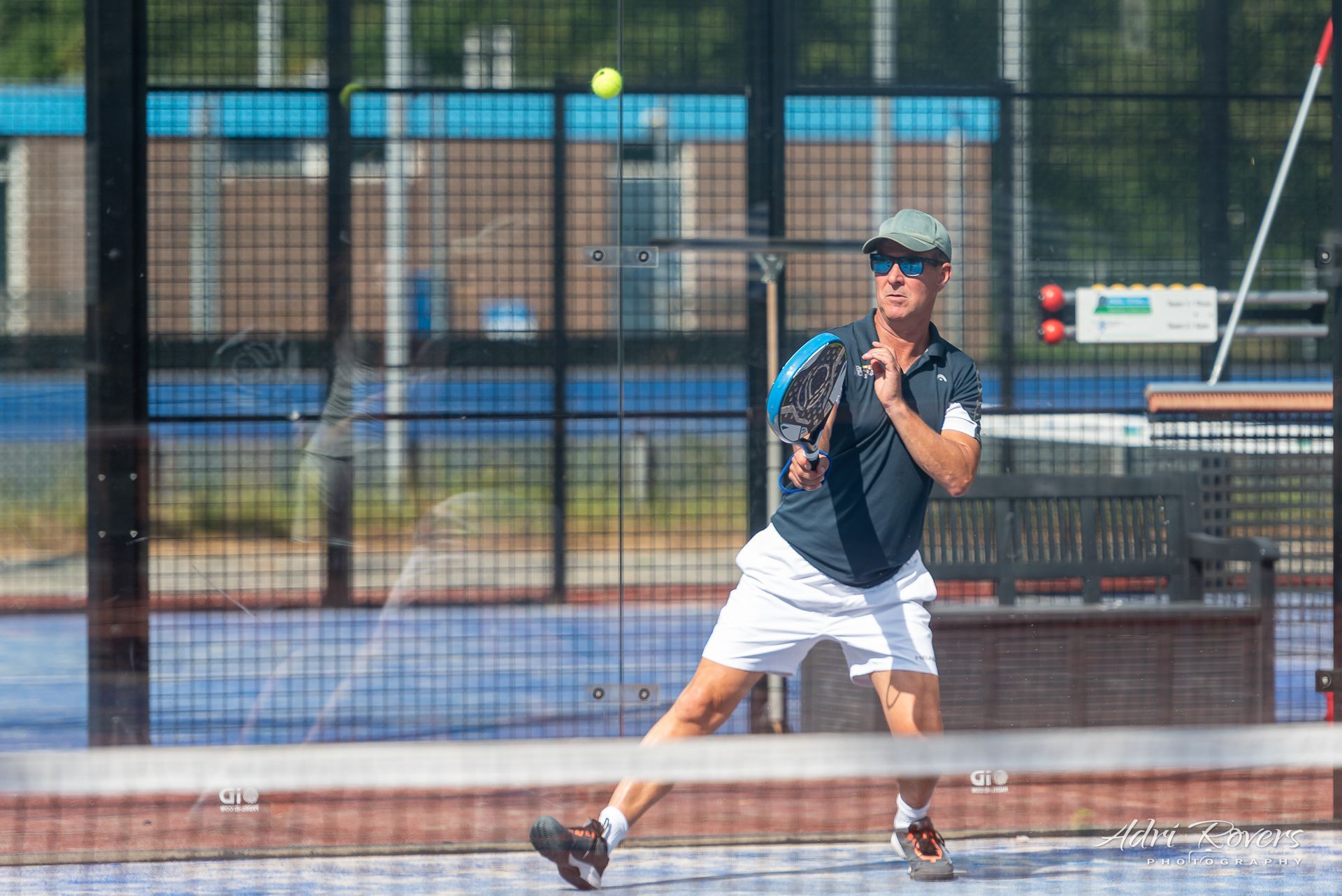 Een man speelt padel op een baan.