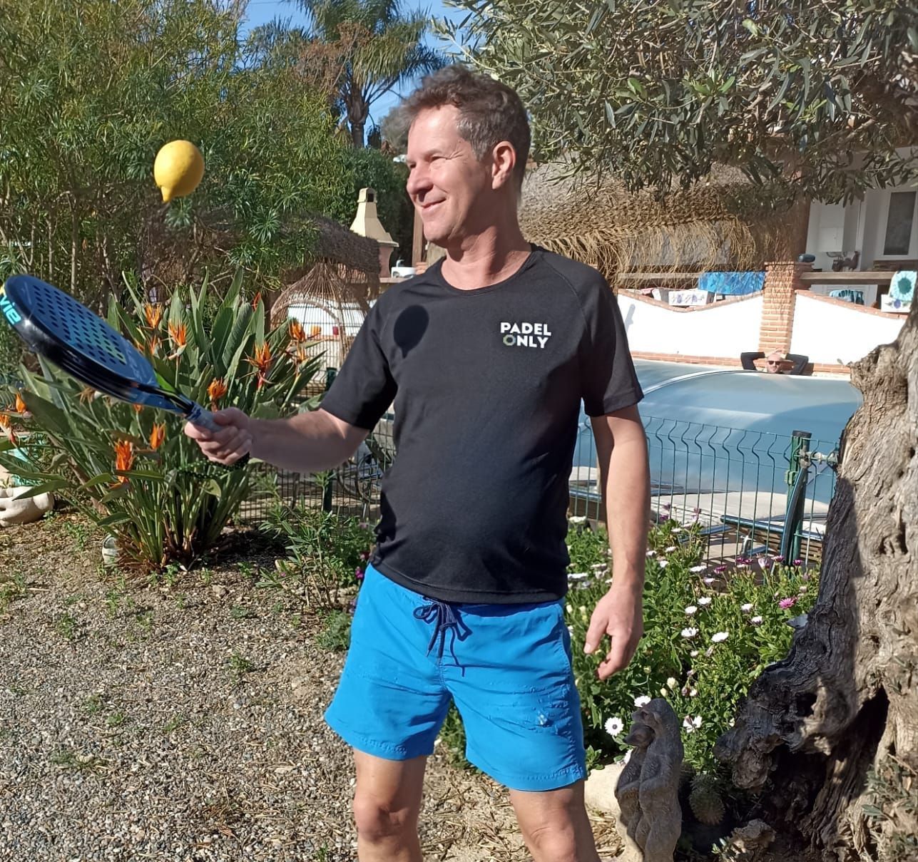 Een man houdt een tennisracket vast voor een zwembad
