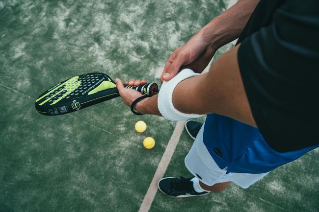 Een persoon houdt een padelracket vast op een padelbaan.