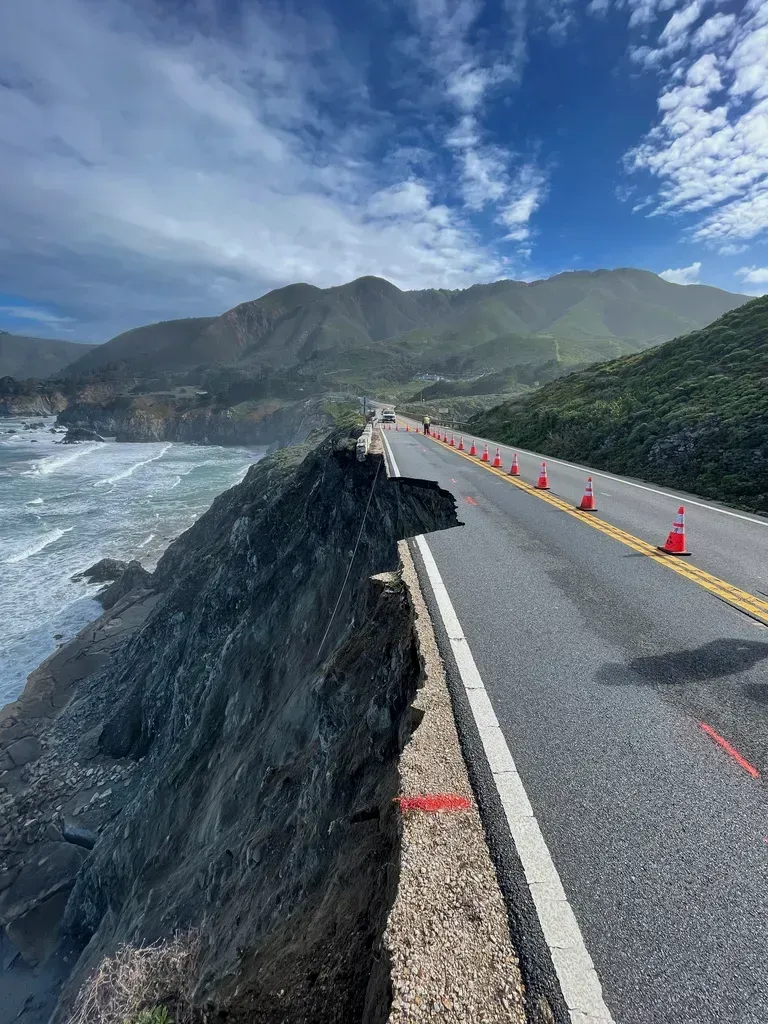 A road with a cliff on the side of it next to the ocean.