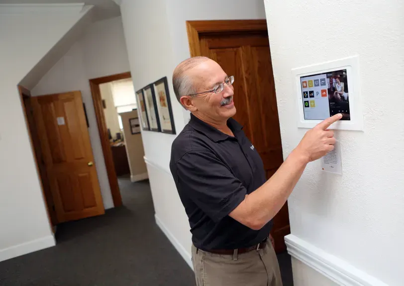 A man in a black shirt is pointing at a screen on a wall