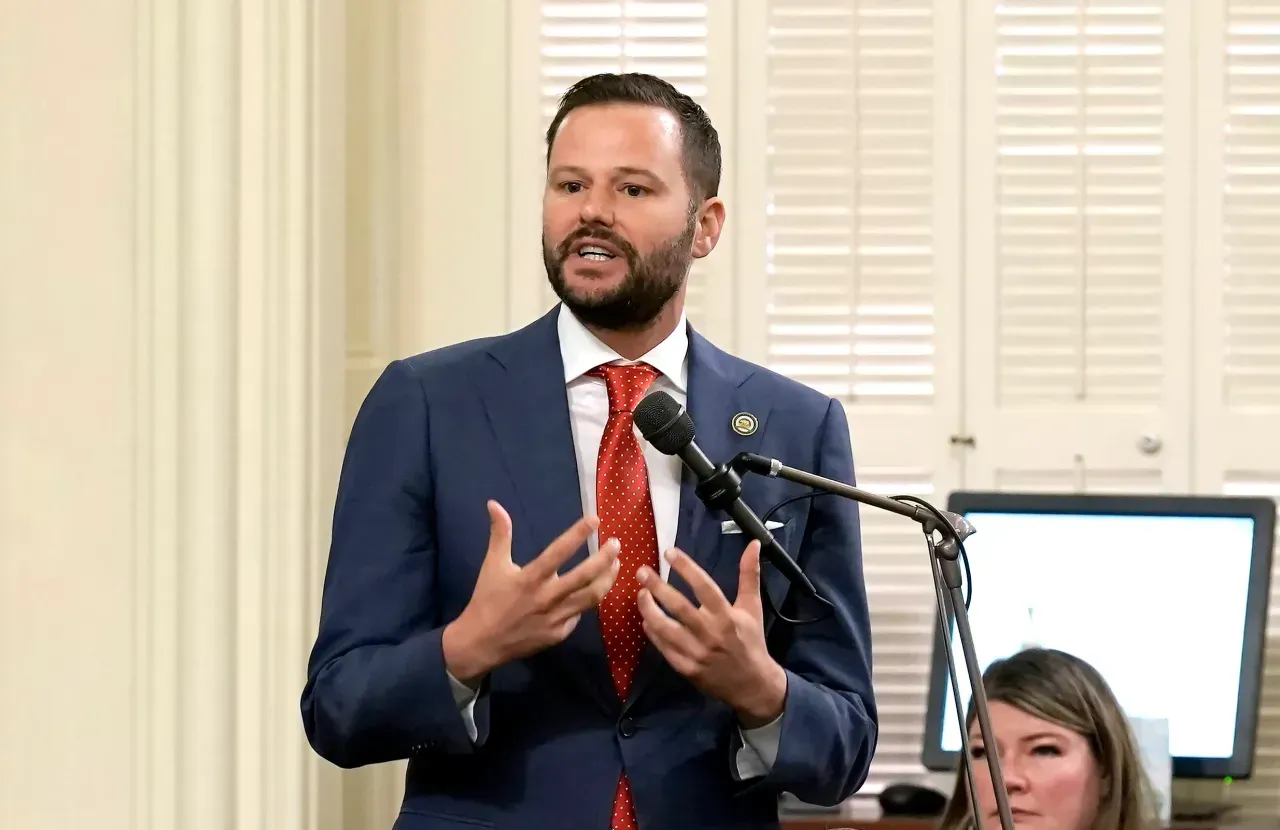 A man in a suit and tie is speaking into a microphone.