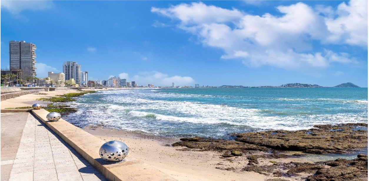 A beach with a soccer ball on the side of it and a city in the background.