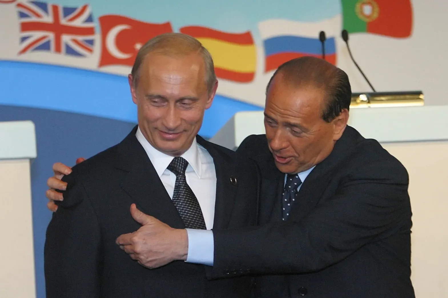 A man in a suit and tie is hugging another man