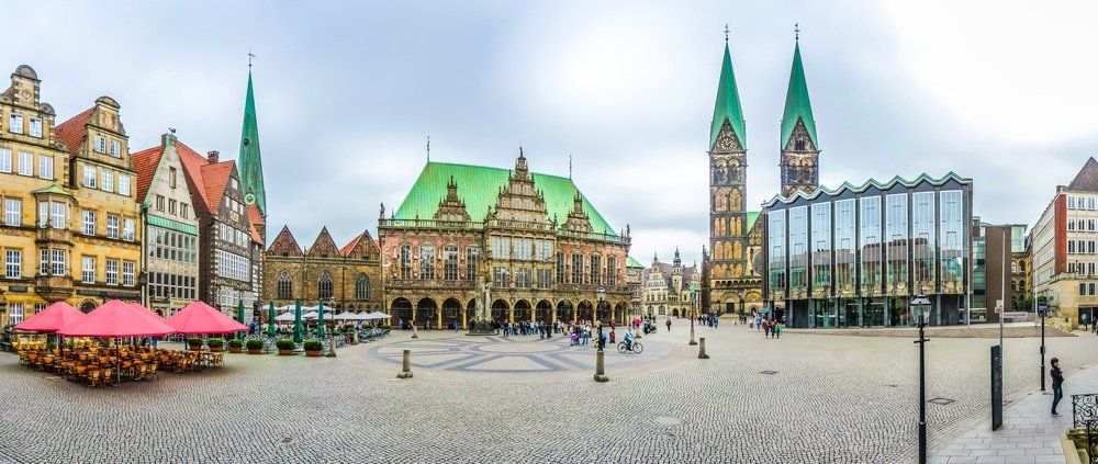 Ein Panoramablick auf einen Stadtplatz mit einem grünen Gebäude und einem Uhrenturm.