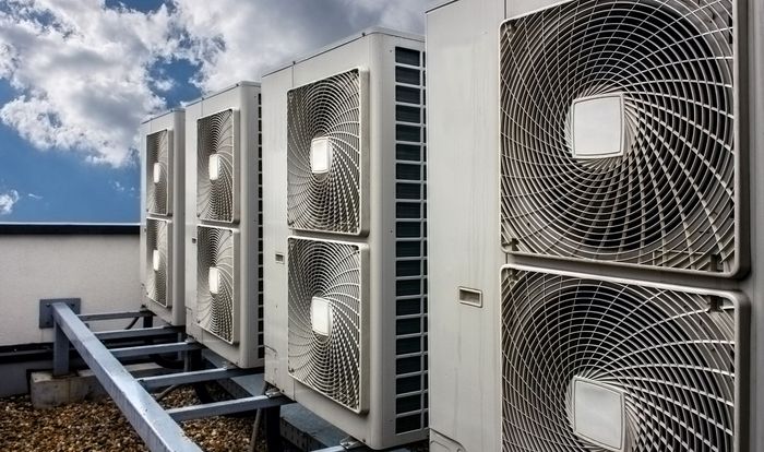 A row of air conditioners are sitting on top of a building.